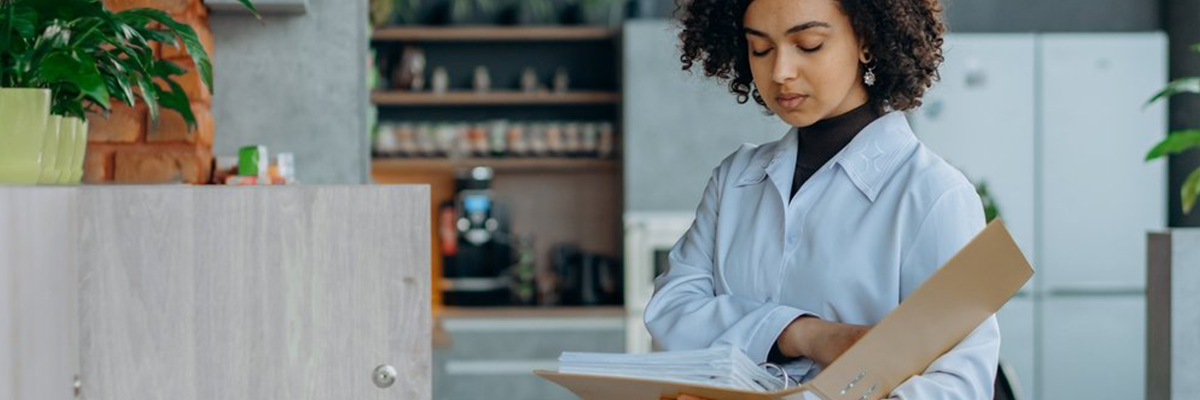 An image of a woman of colour looking up information in a manual.