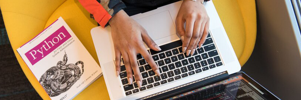 A photograph of a woman's hands on her laptop show from above.