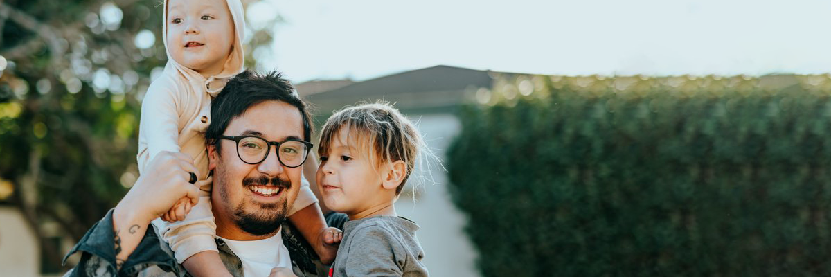 An image of an asian man holding two children.