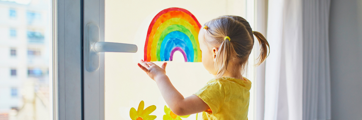 A photographic image of a girl drawing on a window