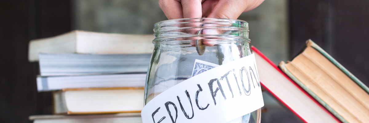 photographic image of a finger putting money in a jar that says education